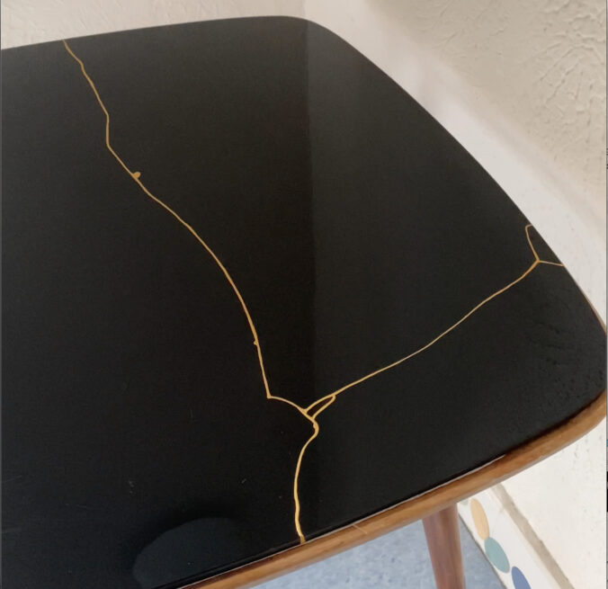 Tisch mit fertig kintsugi-restaurierter Tischplatte aus schwarzem Glas