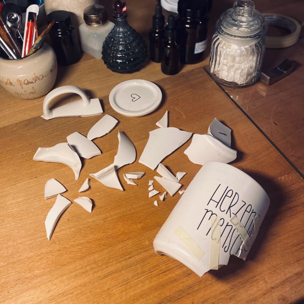Zerbrochene Tasse mit sehr vielen Einzelteilen vor der Kintsugi-Montage