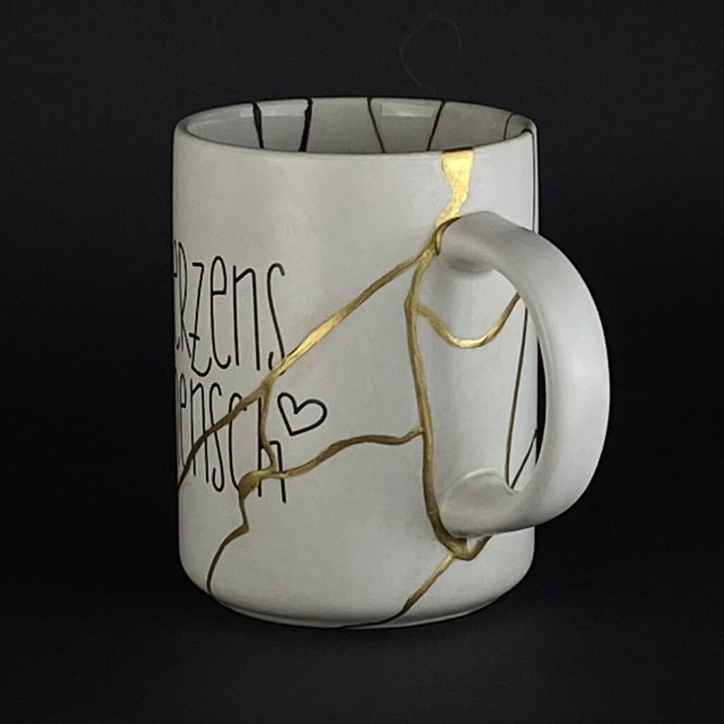 Weiße Herzensmensch Tasse mit vergoldetem Griff nach Kintsugi-Reparatur