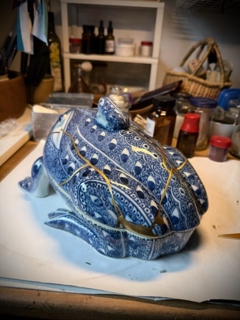 Alt: Seitenansicht der Froschdose mit goldenen Bruchlinien über Kopf, Rücken und Schenkel