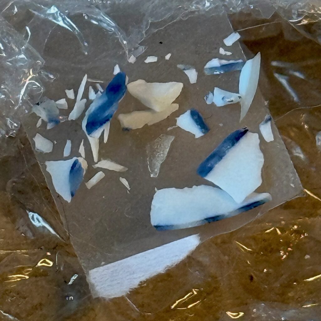 Alt: Kleine weiße und blaue Porzellansplitter in einer durchsichtigen Folie