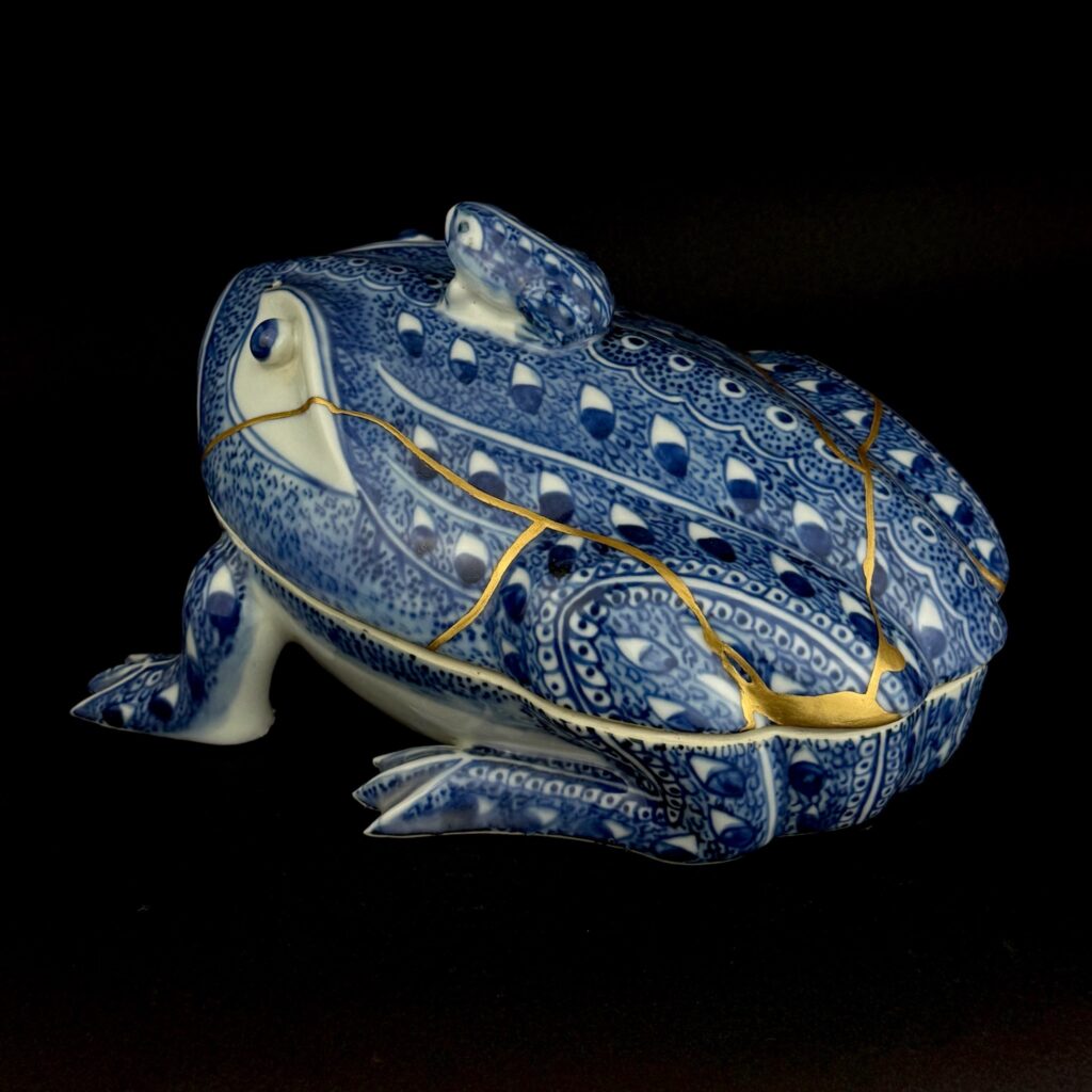 Froschdose von schräg oben, goldene Linien verlaufen über Rücken und Hinterbein